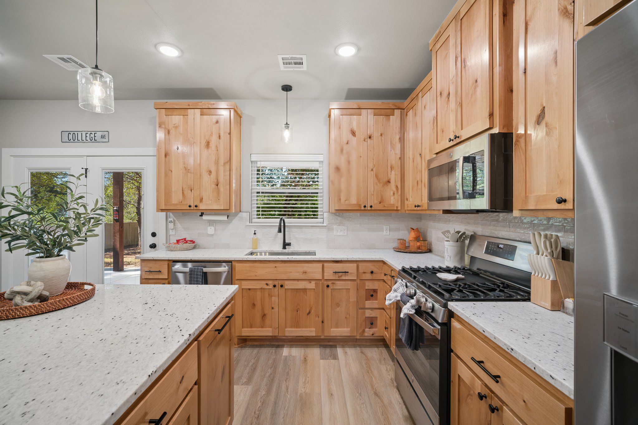 A modern kitchen with wooden cabinets, a stainless steel refrigerator, and a built-in oven.