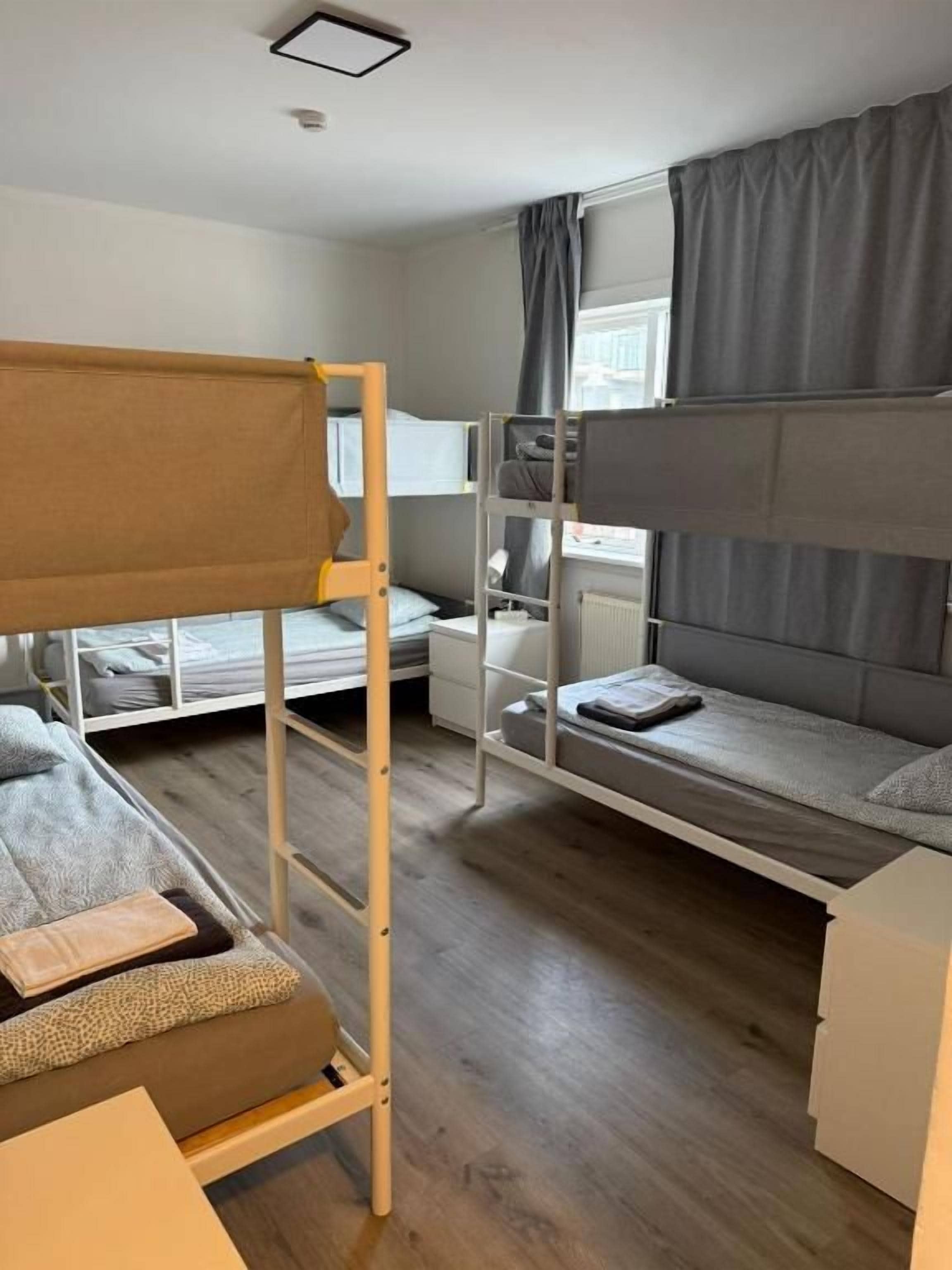 Una camera del dormitorio con letti a castello, una scrivania, una sedia e una finestra con tende.