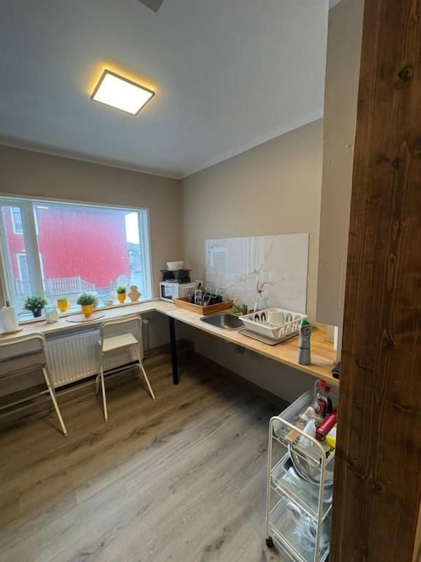 Una cocina con encimera de madera, un radiador blanco y una ventana con vista a un edificio rojo.