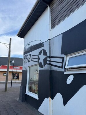 A building with a black and white mural featuring a star and a plane. - WHALE HOUSE (Keflavík)