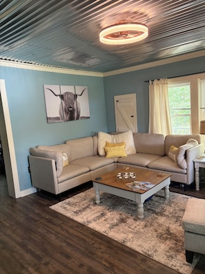 Ein Wohnzimmer mit einer Eckcouch, einem Couchtisch und einem Wandbild.