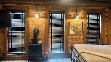 Una habitación con pared de ladrillo, una cama, un armario de madera y un ventilador de techo.