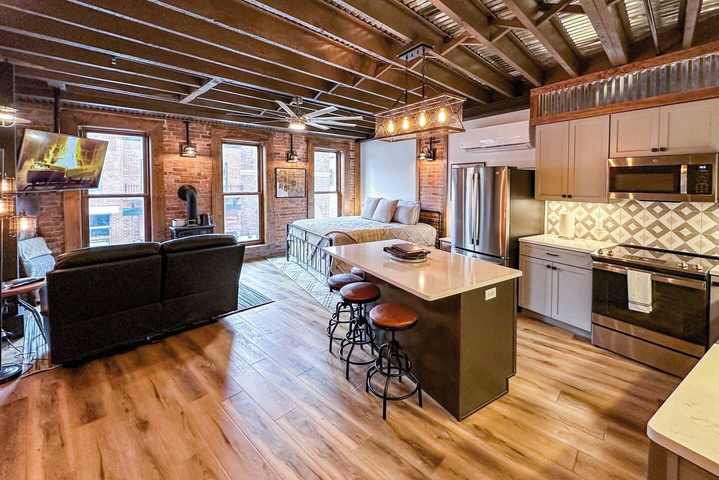 A modern kitchen with a central island, bar stools, and stainless steel appliances.