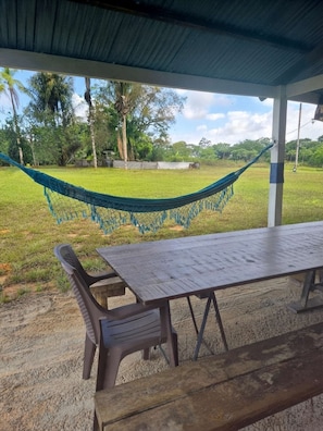 A covered outdoor area with a hammock, a table, and chairs.