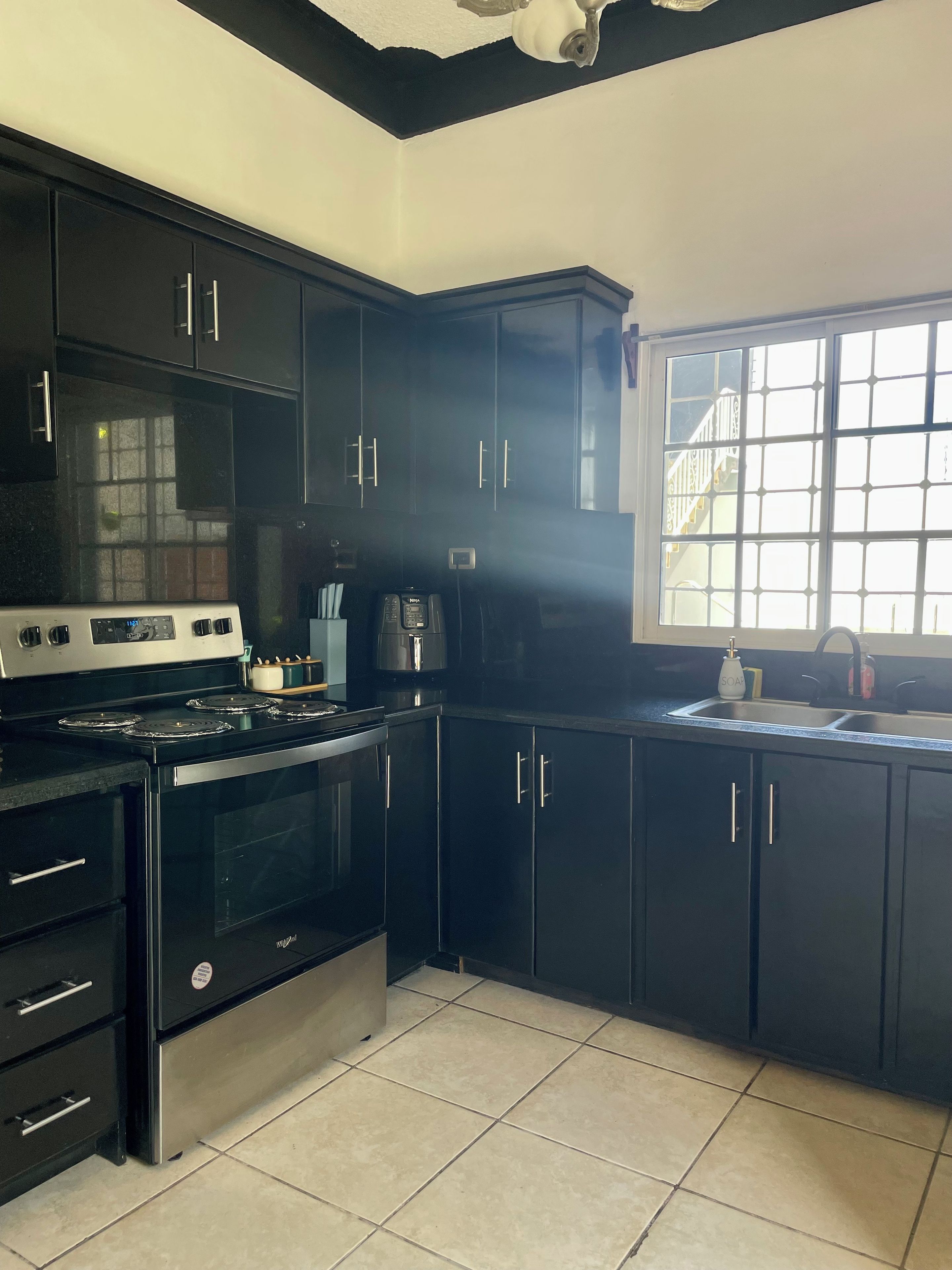 A kitchen with black cabinets, a stove, and a window with a view.