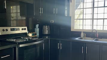 A kitchen with black cabinets, a stove, and a window with a view.
