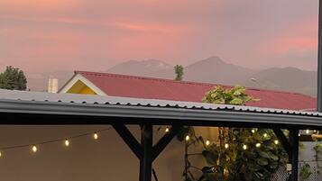 A covered outdoor area with a hammock, string lights, and a view of distant mountains.