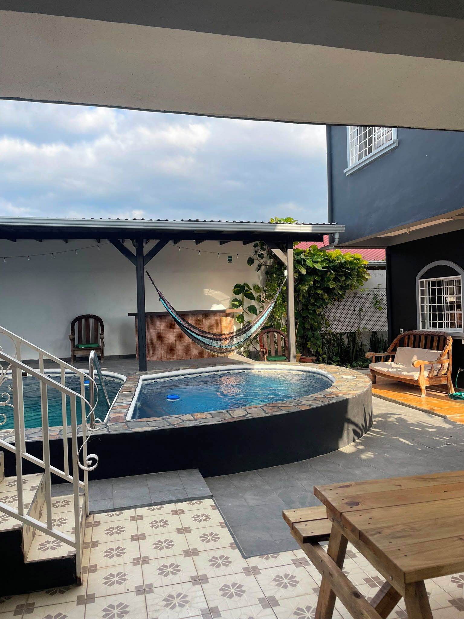 A swimming pool with a hot tub, a hammock, and outdoor furniture.