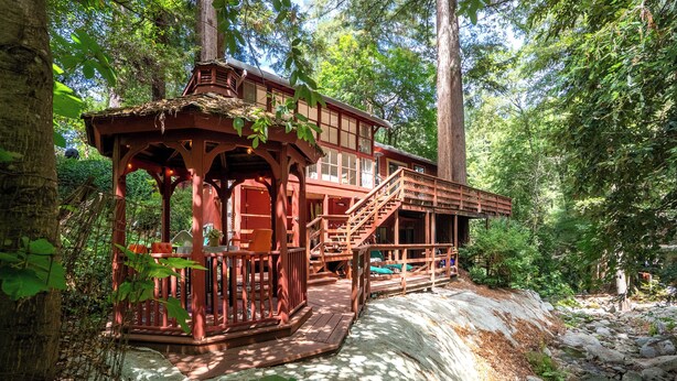 A wooden cabin with a covered porch and a staircase leading to a deck.
