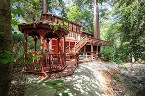 A wooden cabin with a covered porch and a staircase leading to a deck.