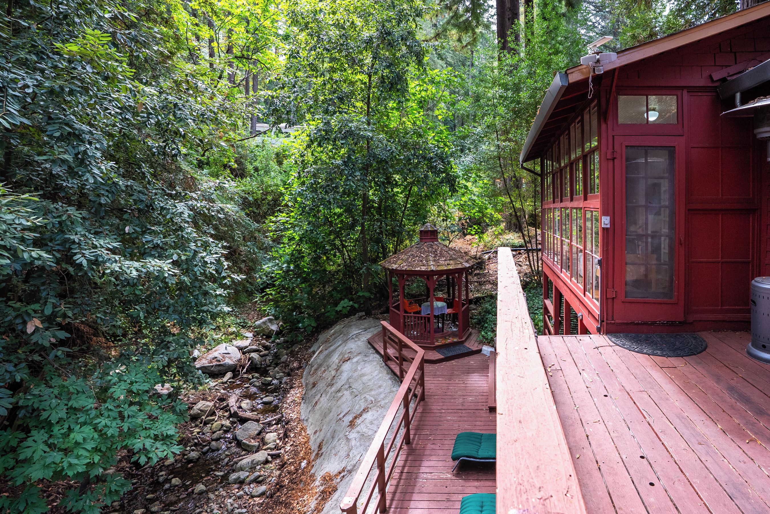 Une terrasse en bois avec un belvédère et un bâtiment rouge doté de grandes fenêtres.