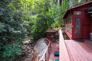 A wooden deck with a gazebo and a red building with large windows.