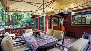 An outdoor patio with a table and chairs, a covered area, and a view of a red building with a 'HOME' sign.