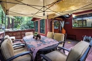 Un patio exterior con mesa y sillas, un área techada y vista a un edificio rojo con un letrero que dice 'HOME'.