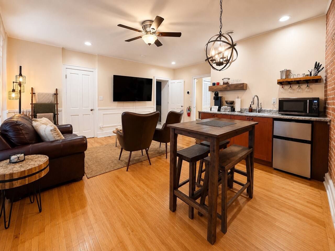 A modern living room with a sofa, chairs, a dining table, and a kitchen area with a microwave.