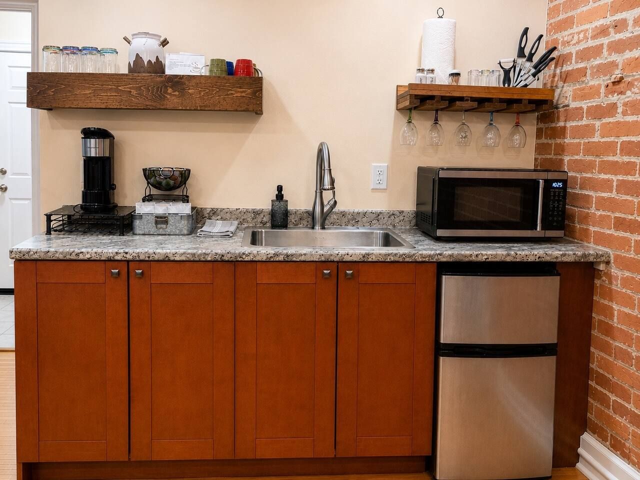 A kitchen with wooden cabinets, a stainless steel refrigerator, a microwave, a coffee maker, and a sink.