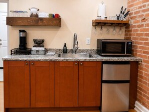 A kitchen with wooden cabinets, a stainless steel refrigerator, a microwave, a coffee maker, and a sink.