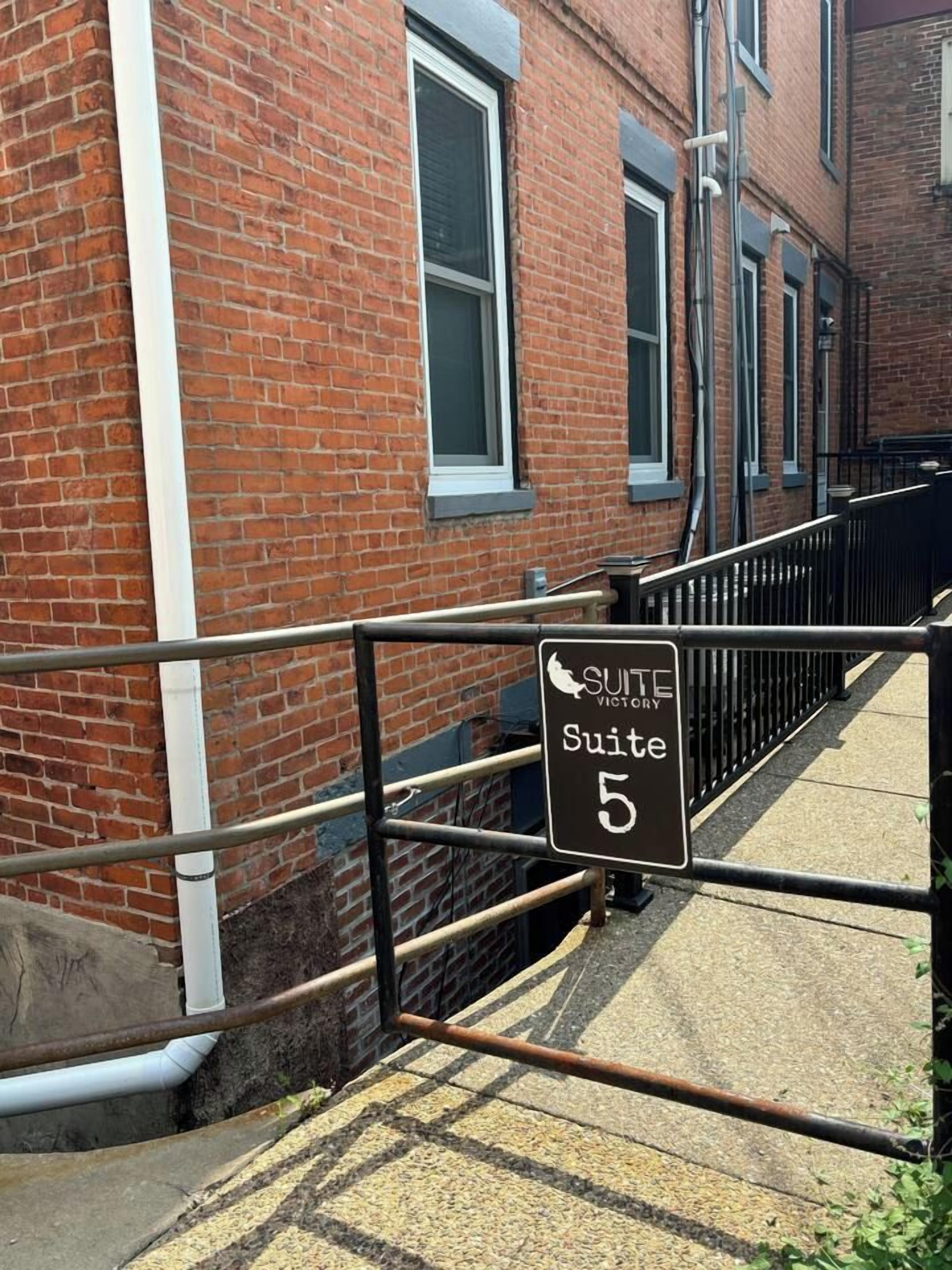 A brick building with a sign indicating 'Suite 5' and a metal gate.