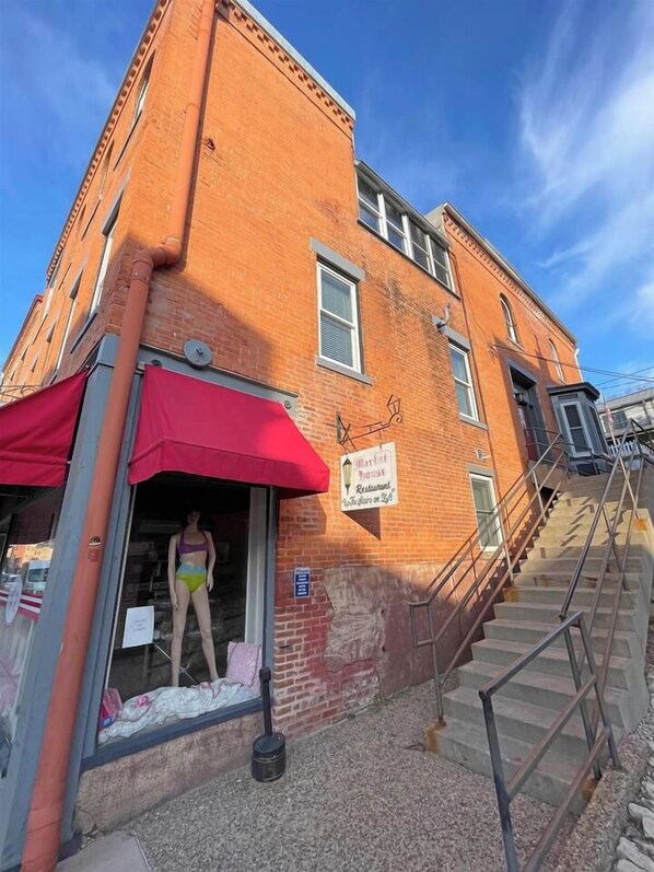 A brick building with a red awning and a staircase leading to an upper level.