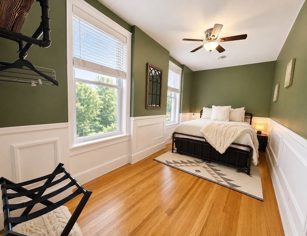 Ein Schlafzimmer mit einem Bett, einem Deckenventilator, einem Fenster und einem Sessel.