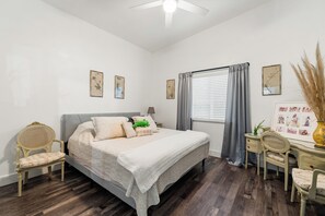 A bedroom with a bed, two chairs, a desk, and a window with curtains. - Newly Constructed 1-bedroom guest house near Arden Park (Sacramento)