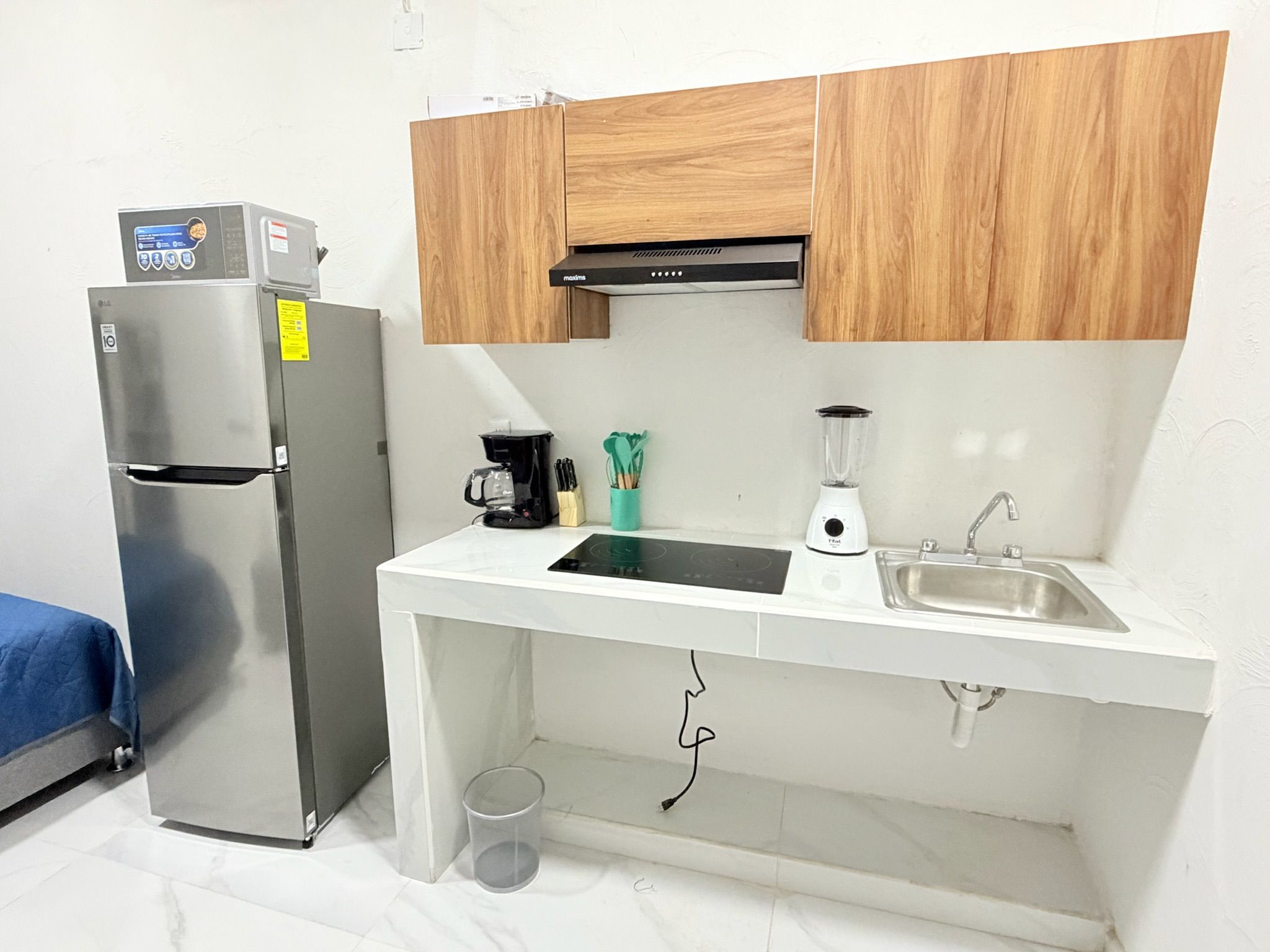 Una kitchenette funcional con refrigerador, estufa, pileta y gabinetes de madera.