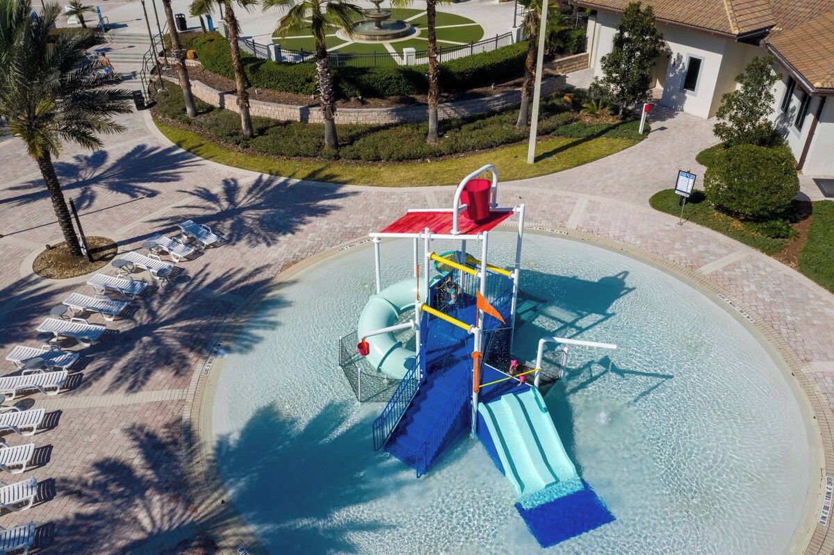 A water park with a water slide, lounge chairs, and palm trees.