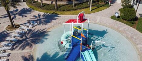 A water park with a water slide, lounge chairs, and palm trees.