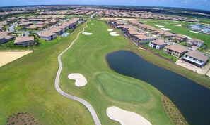 An aerial view of a residential area with houses, a golf course, and a lake. - Near Disney 8BR Villa with Pool, Spa and Cinema (Kissimmee)