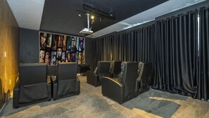 Ein Heimkino mit Projektor, mehreren Sitzbereichen und einer Wand voller Filmplakate.