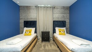 Ein Doppelzimmer mit zwei Betten, jeweils mit Kopfteil, einem kleinen Nachttisch und einem Vorhang.