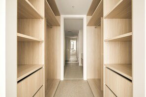 Ein Flur mit Holzbögen auf beiden Seiten, der zu einem Zimmer mit Bett und Fenster führt.