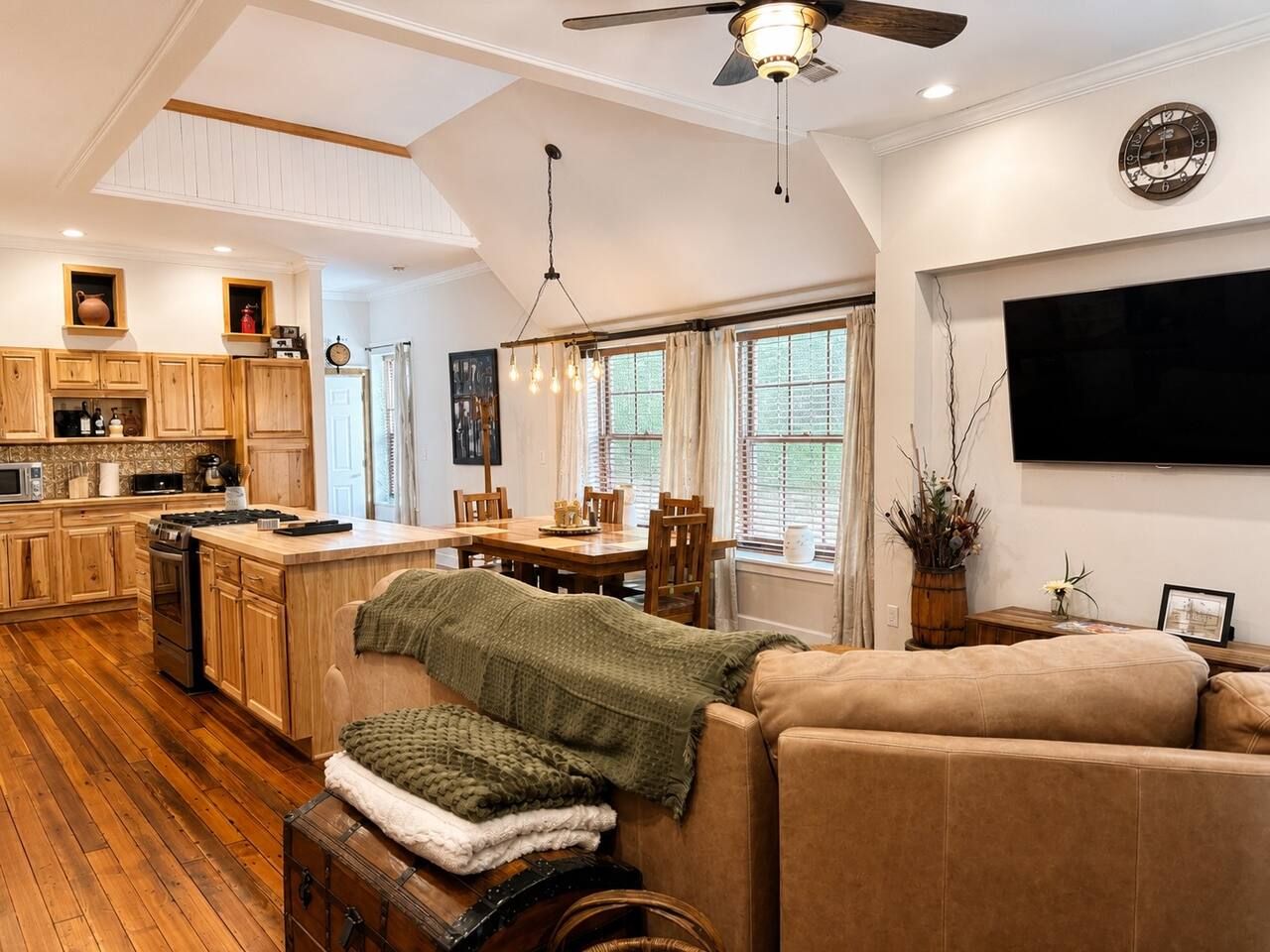 A spacious living area with a sofa, a dining table, and a kitchen with wooden cabinets and a stove.