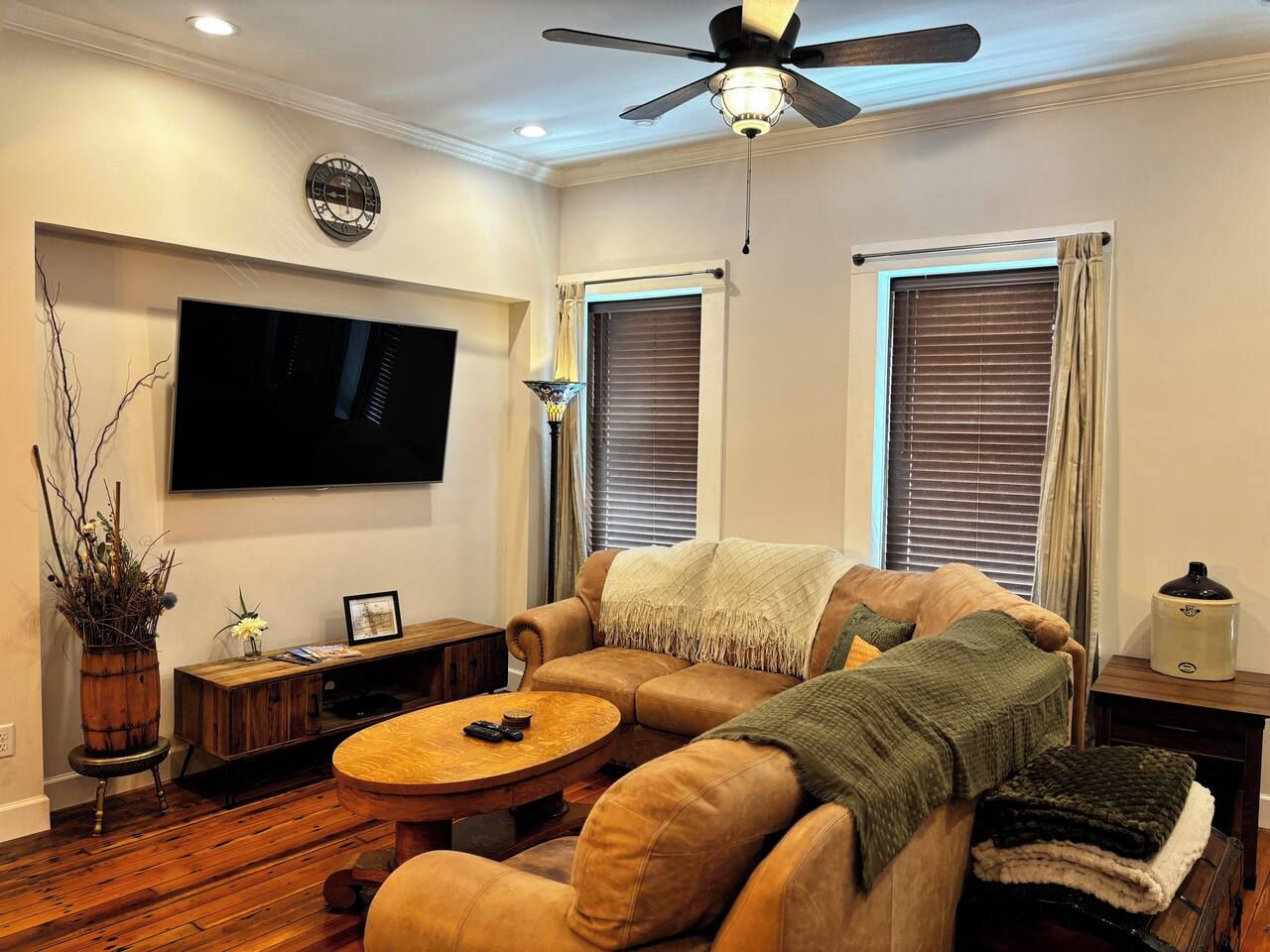 Una sala de estar con sofá, mesa de centro, televisor y ventilador de techo.