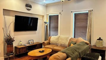 Una sala de estar con sofá, mesa de centro, televisor y ventilador de techo.