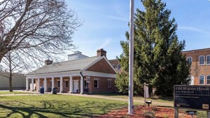 A historic building with a covered porch, a flagpole, and a sign indicating it is a state historic site and information center. - Suite Victory #7 On Main St w/Reserved Parking (Galena)