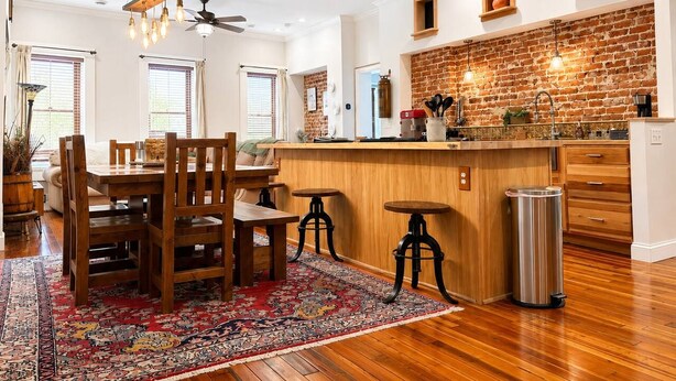 A spacious kitchen with a brick backsplash, wooden bar counter, and modern lighting fixtures. - Suite Victory #7 On Main St w/Reserved Parking (Galena)