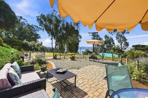Un espace extérieur aménagé en terrasse, avec des sièges, une table et des parasols.