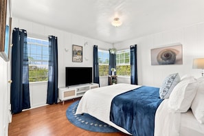 Un dormitorio con cama, televisión y ventana con cortinas.