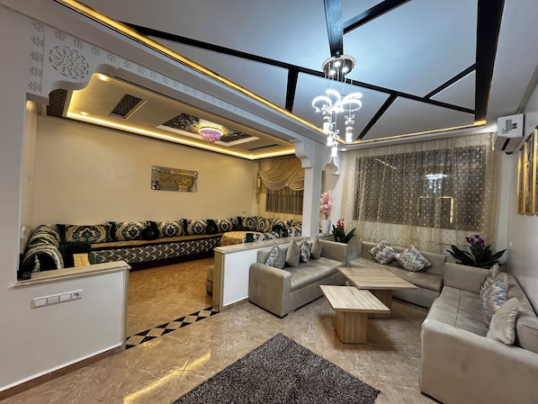 A modern living room with a sofa set, a coffee table, and a decorative chandelier.