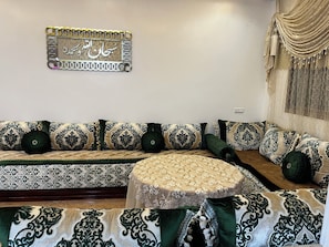 A room with a sofa set, a round table, and a decorative wall piece.