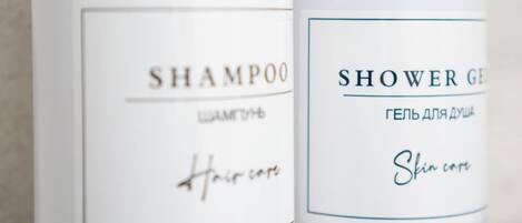 Two white bottles with wooden pump dispensers, one labeled 'SHAMPOO' and the other 'SHOWER GEL' with Cyrillic text.