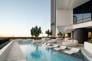 A rooftop pool area with lounge seating and a view of the city skyline. - Highfloor Queens Wharf Riverview 1BR *Pool & GYM* (Brisbane City)
