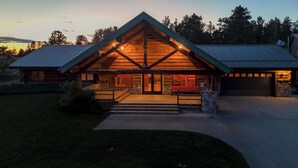 A log cabin with a prominent gabled roof, a stone foundation, and a front porch with steps leading to the entrance. - Peaceful Montana Ranch Getaway (Custer)