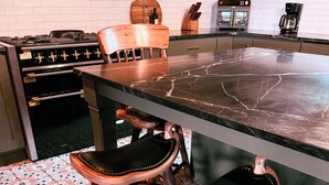 A kitchen with a marble countertop, wooden chairs with leather seats, and a patterned tile floor. - Peaceful Montana Ranch Getaway (Custer)