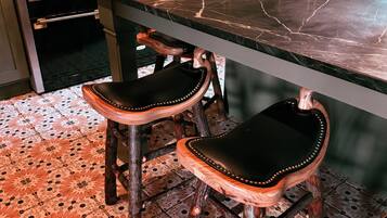 Une cuisine dotée d’un plan de travail en marbre, de chaises en bois avec des assises en cuir et d’un sol carrelé à motifs.