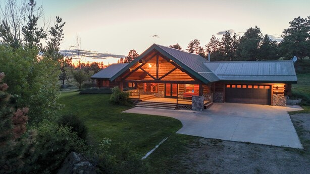 A log cabin with a large porch, stone foundation, and a garage. - Peaceful Montana Ranch Getaway (Custer)