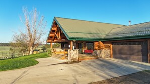 A log cabin with a stone foundation, a green metal roof, and a garage. - Peaceful Montana Ranch Getaway (Custer)