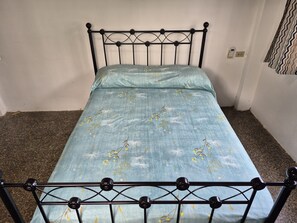 En säng för en person med en metallram och ett blommigt överkast.