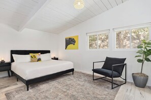 A bedroom with a bed, bedside tables, a chair, a potted plant, and a window with a view of trees. - Modern Spacious Baja w/ Hot Tub near SDSU, Downtown San Diego, Navy (San Diego)
